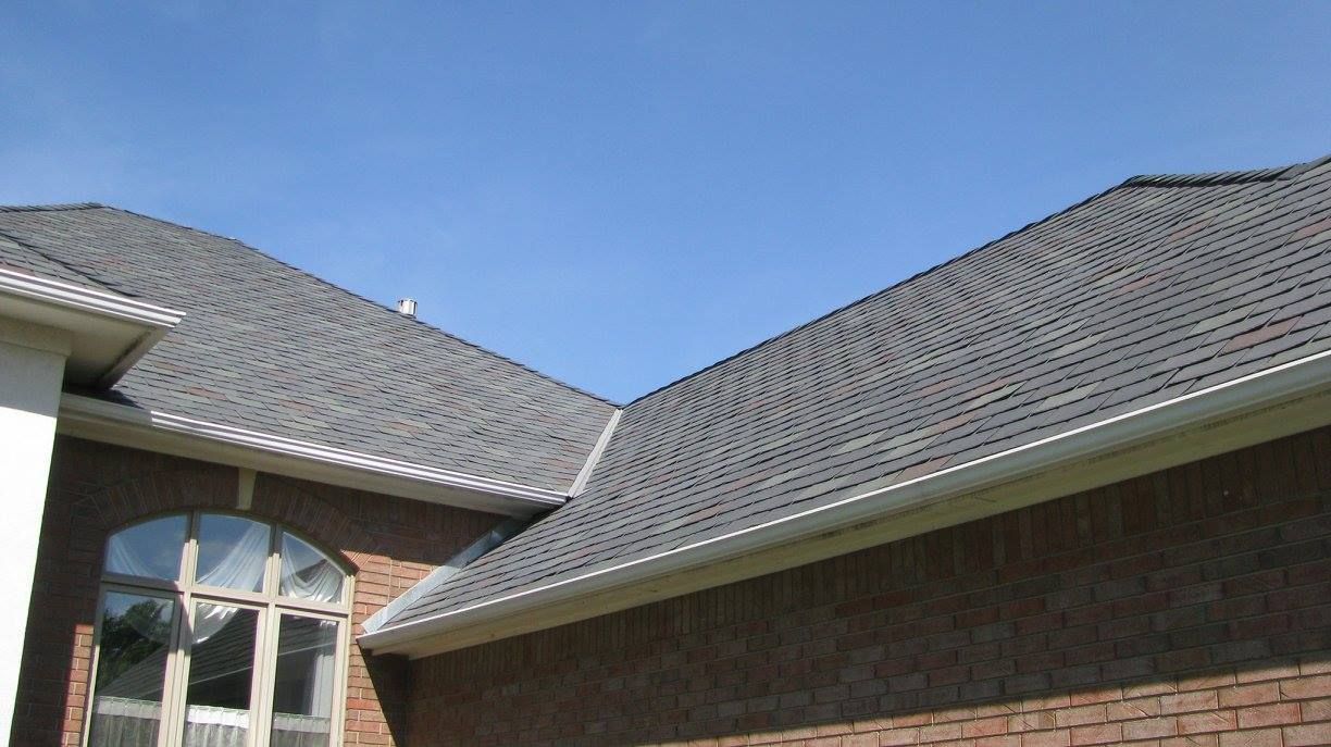 A brick house with a gray roof and a blue sky in the background
