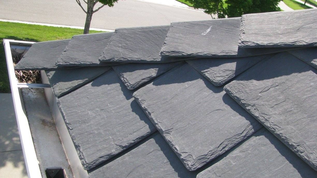 A roof with a gutter and a tree in the background