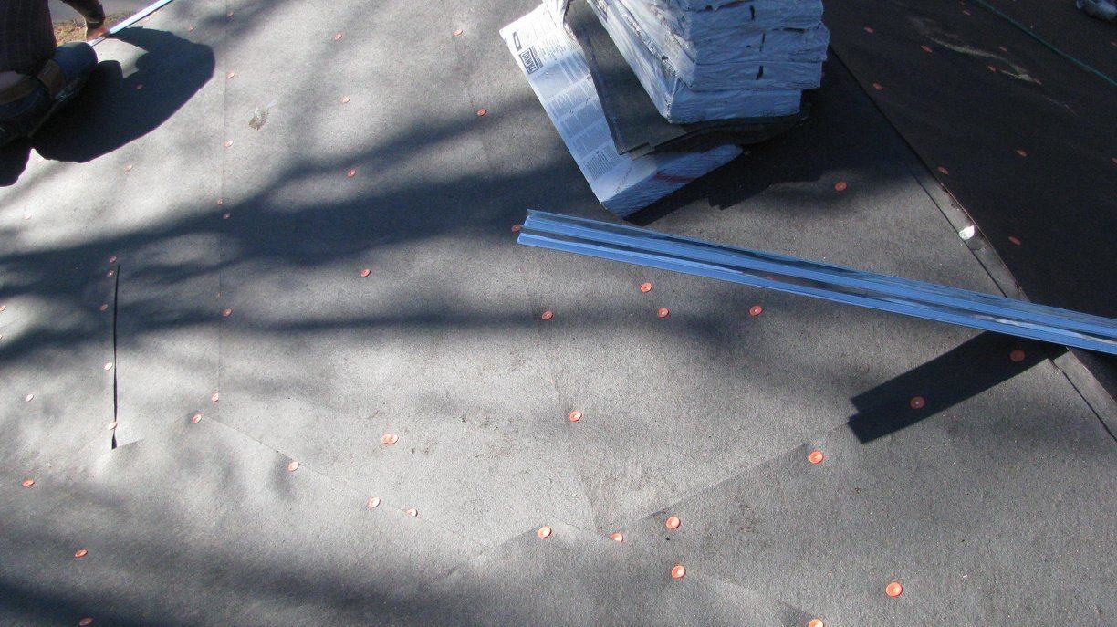 A piece of metal is laying on the ground next to a stack of bricks.