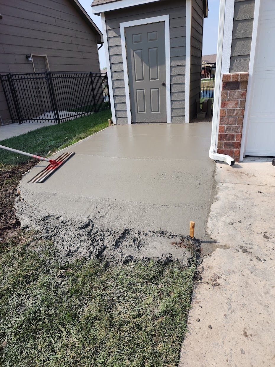 A concrete walkway is being built in front of a shed.