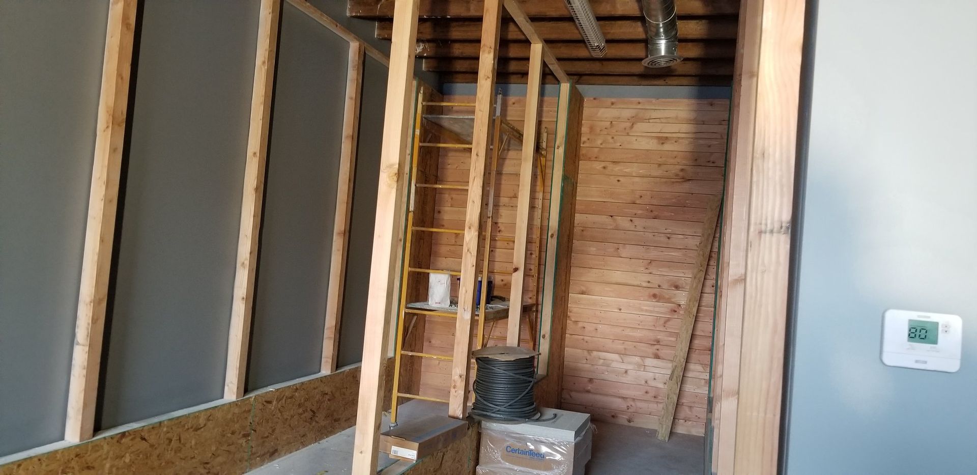 A room with wooden walls and a thermostat on the wall.