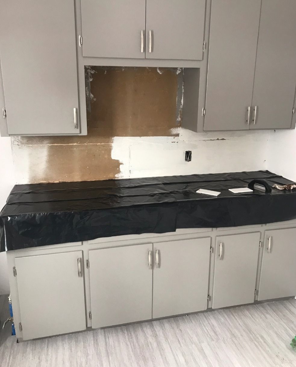 A kitchen with white cabinets and a black counter top.