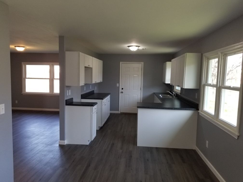 An empty kitchen with white cabinets and black counter tops