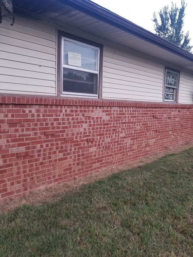 A house with a red brick wall and white siding.