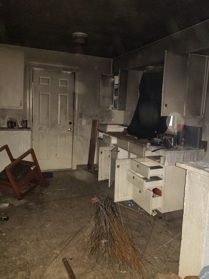 A kitchen with a rocking chair and a broom in it.