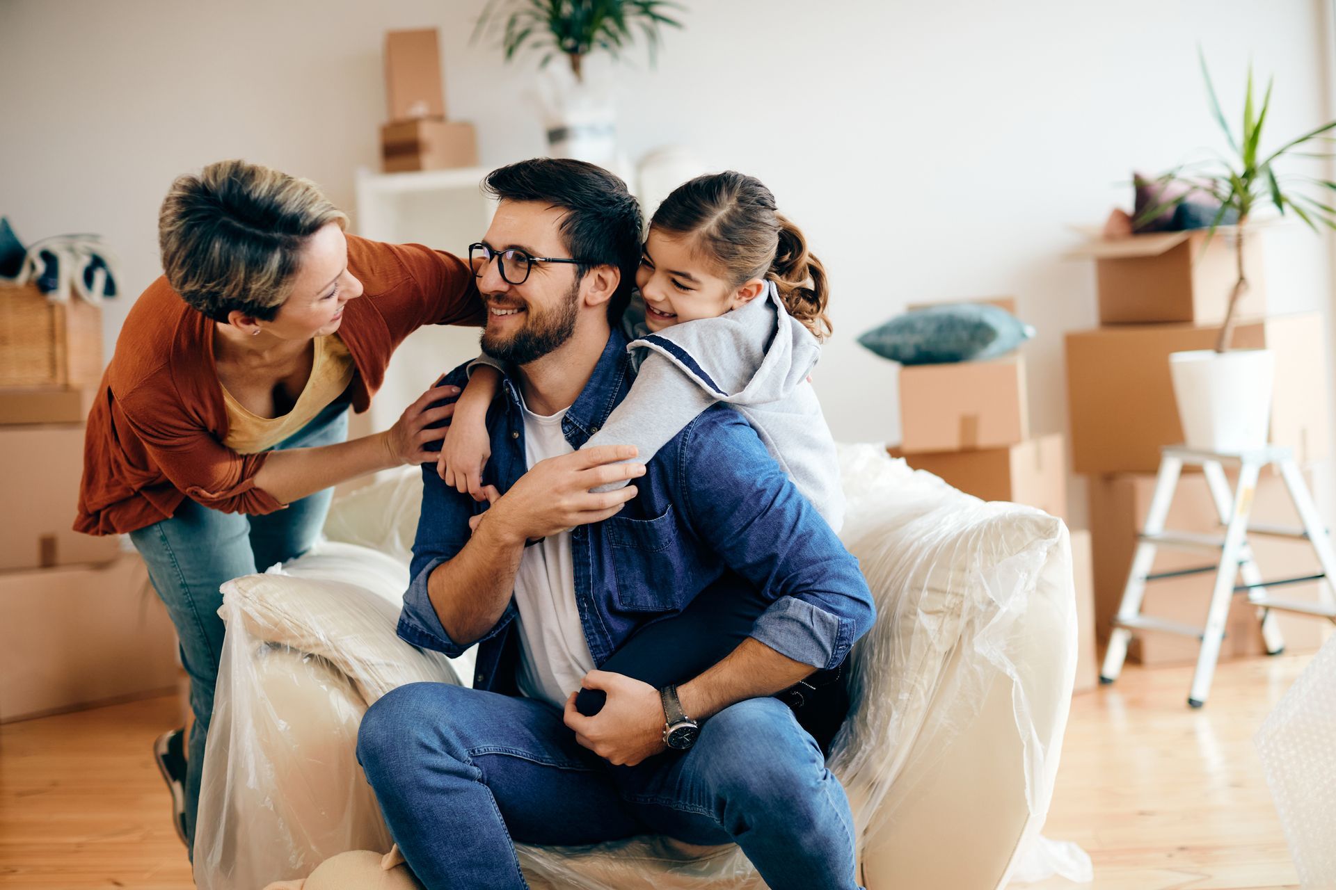 Family in new home: parents and child smiling, boxes in background.