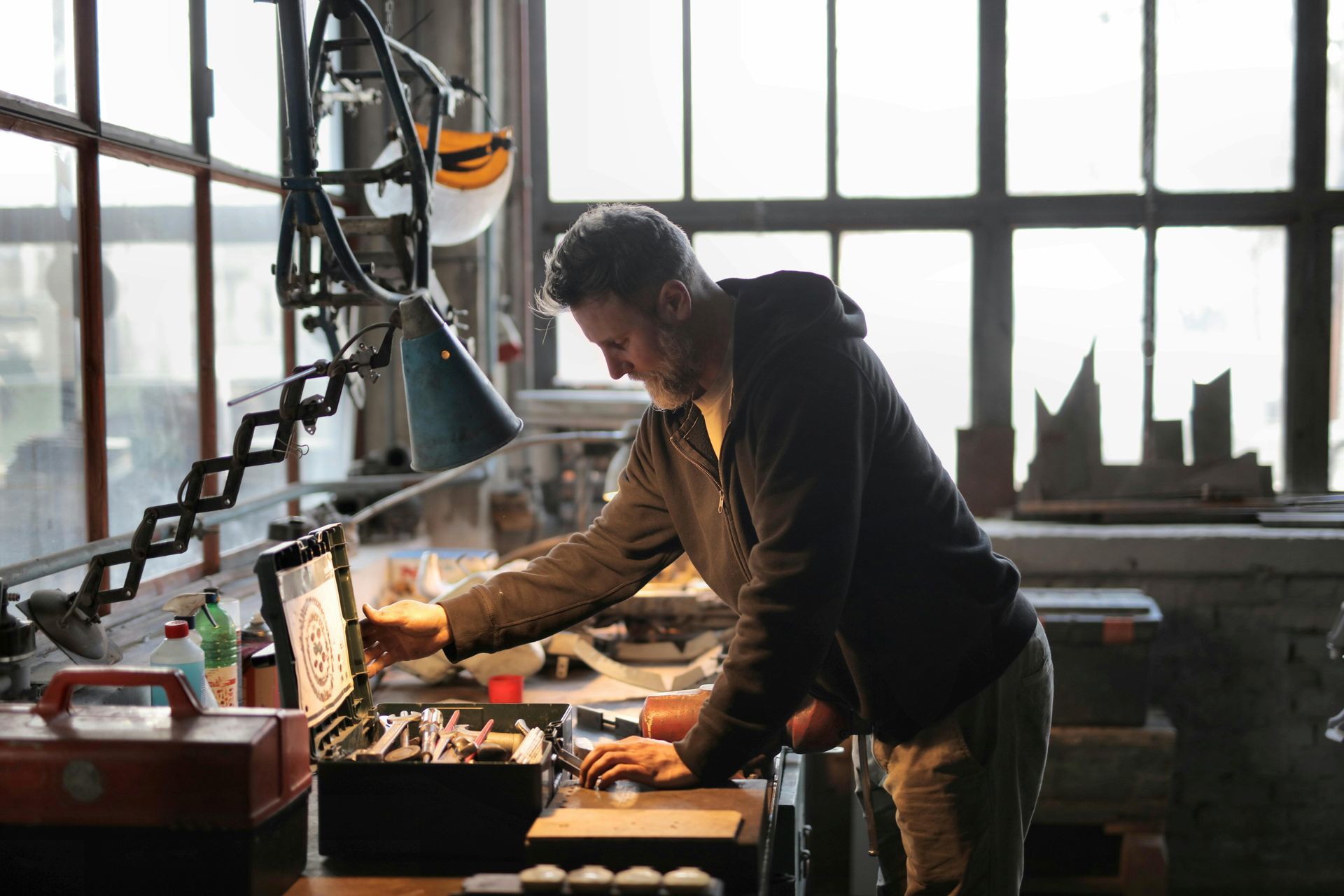 Man in workshop looking at tools in open toolbox.