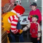 Mcdonald 's mascot is talking to a young boy in a restaurant.