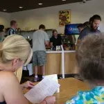 A woman is sitting at a table reading a menu in a restaurant.