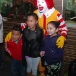 A group of children are posing for a picture with mcdonald 's clown.