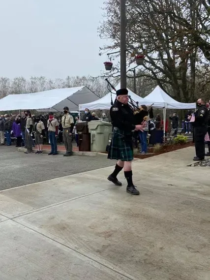 A man in a kilt is playing bagpipes in front of a crowd
