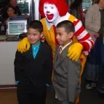 Two young boys are posing for a picture with mcdonald 's mascot.