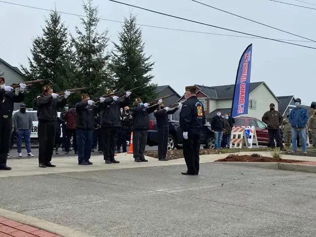 A group of men are saluting in front of a flag that says ' freedom ' on it
