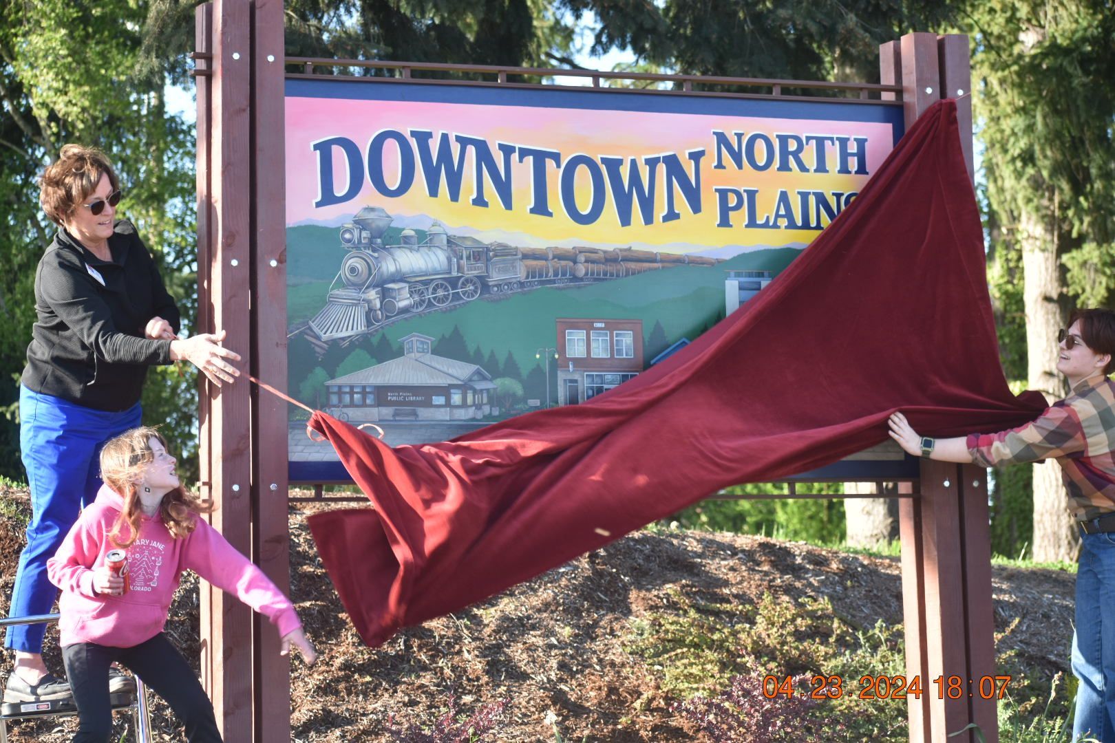 People unveil a sign that says downtown north plains