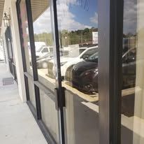 A storefront with a dark metal frame. Reflections of cars and the outside can be seen in the large glass windows.