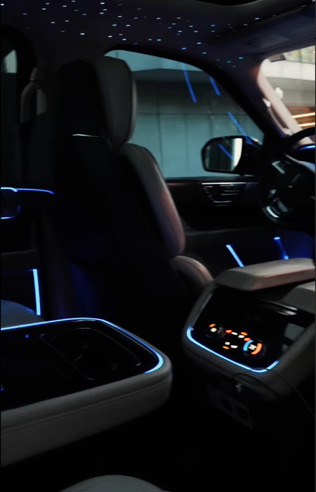 Interior of a luxury SUV with starry ceiling, ambient blue lighting, and cream-colored seats.