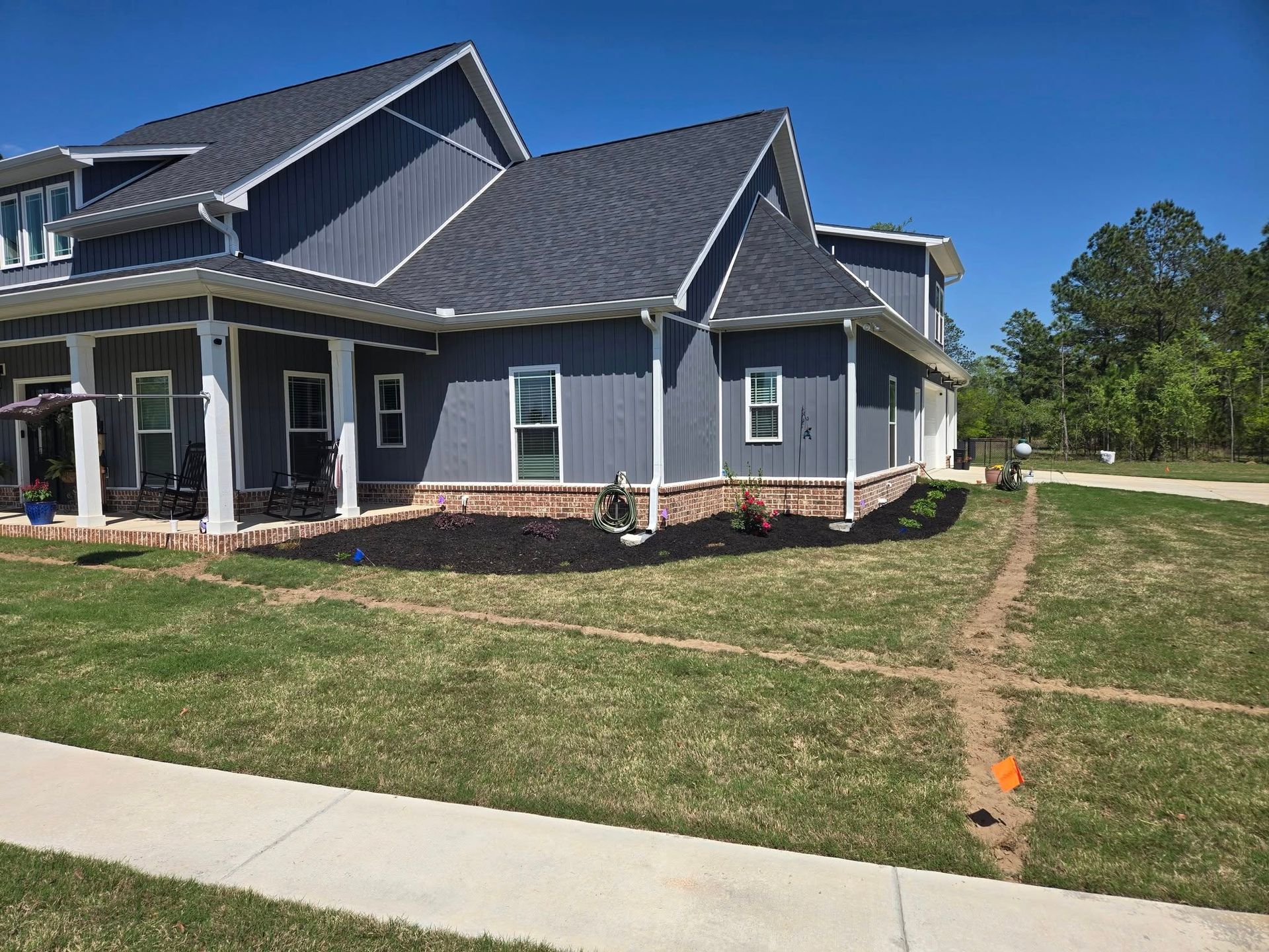 A large house with a gray roof is sitting on top of a lush green lawn.