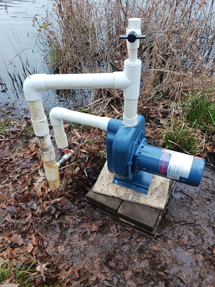 A blue and white pump is sitting next to a body of water.