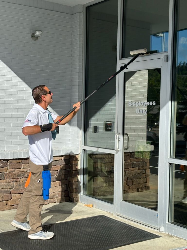 A man is cleaning a glass door with a mop.