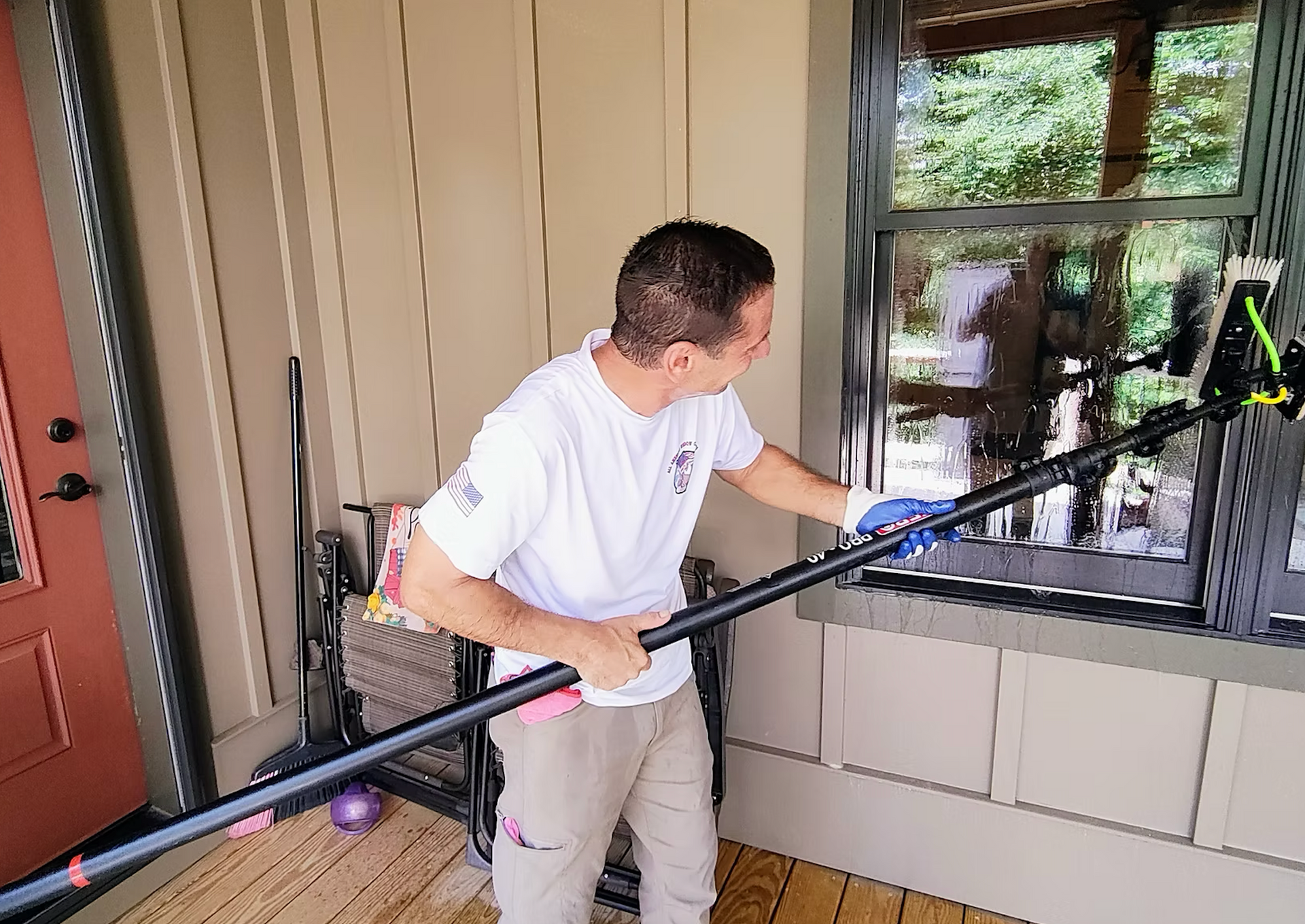 A man is cleaning a window with a long pole.