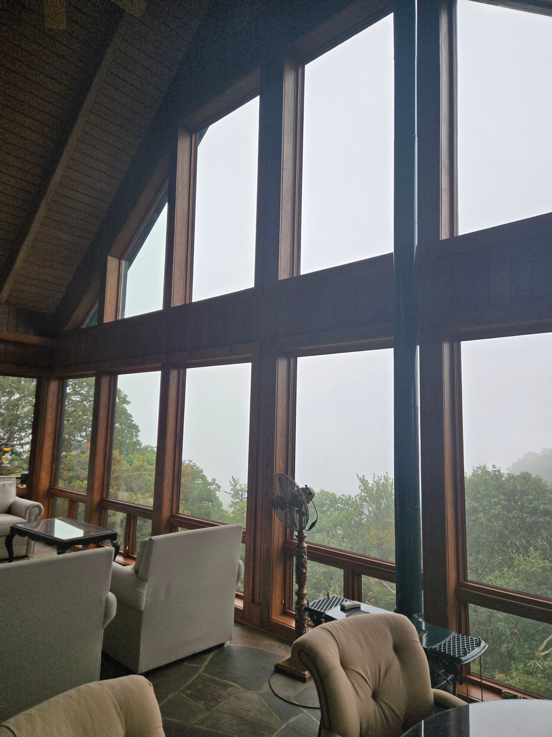 A living room with a lot of windows and trees in the background