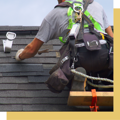 A man wearing a harness is working on a roof.