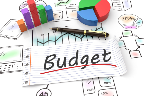  A desk with the words Budget surrounded by a pen, graphs and percentage images