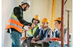 A man in a hard hat is holding a large piece of wood ..