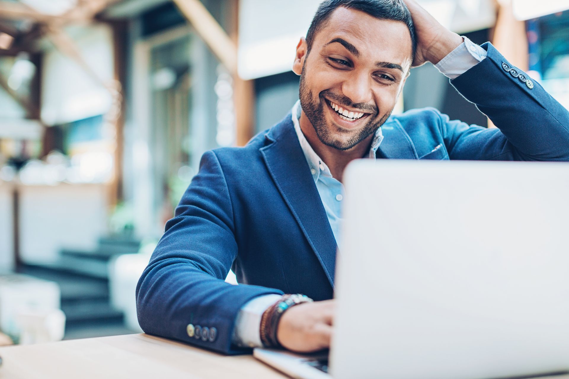 A man in a suit is sitting at a table using a laptop computer.