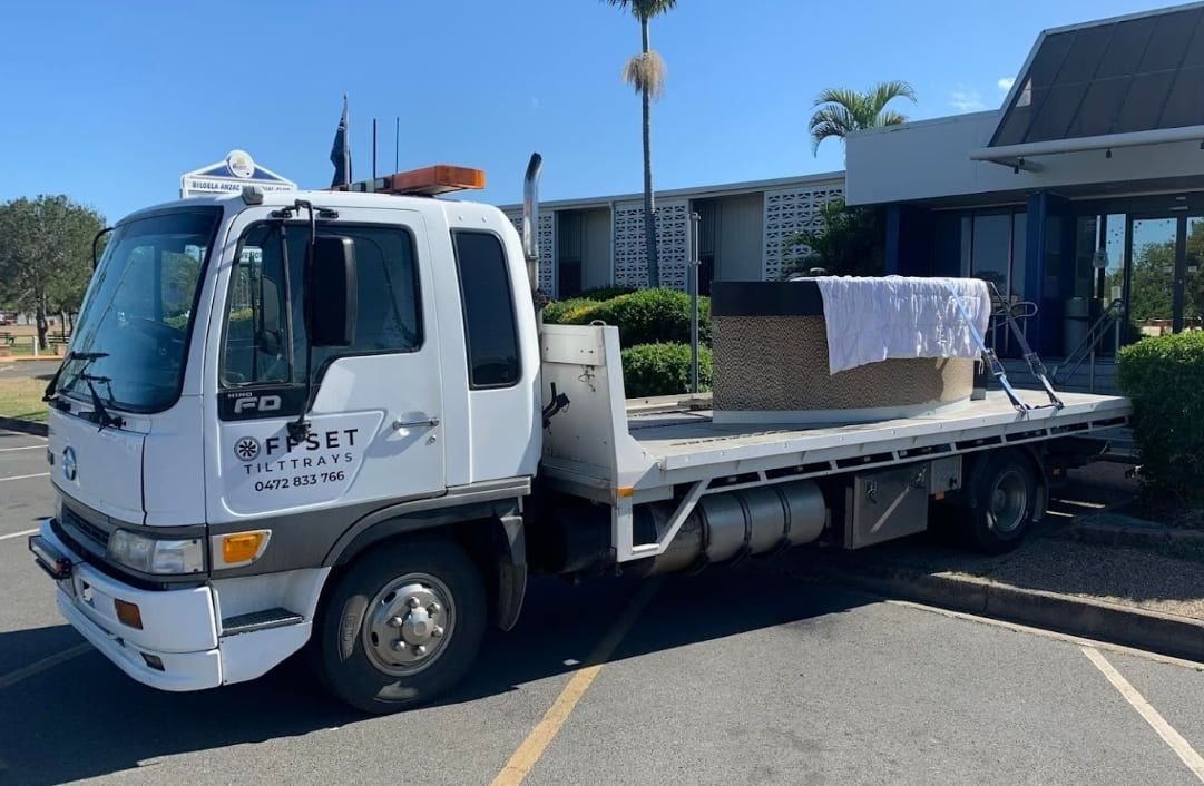 A White Tow Truck Is Parked In A Parking Lot In Front Of A Building — Offset Tilt Trays In Biloela, QLD