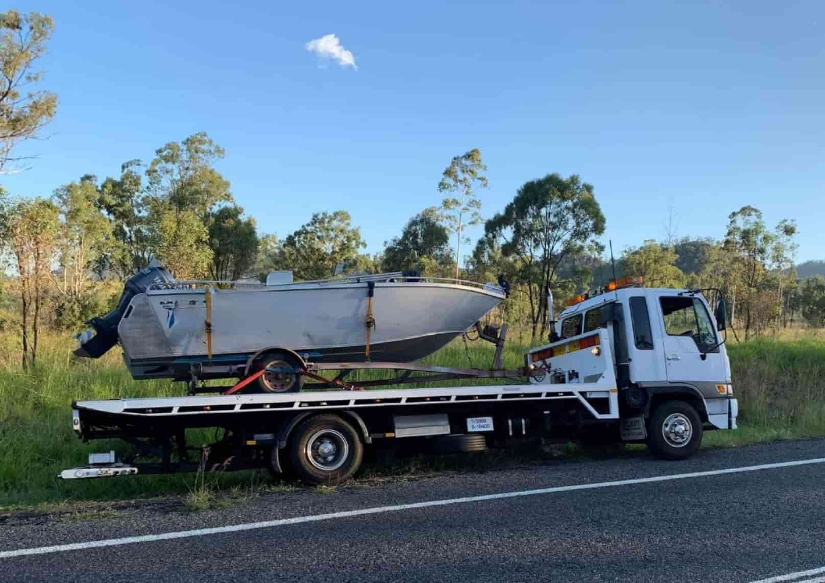 A Tow Truck Is Carrying A Boat Down The Road — Offset Tilt Trays In Biloela, QLD