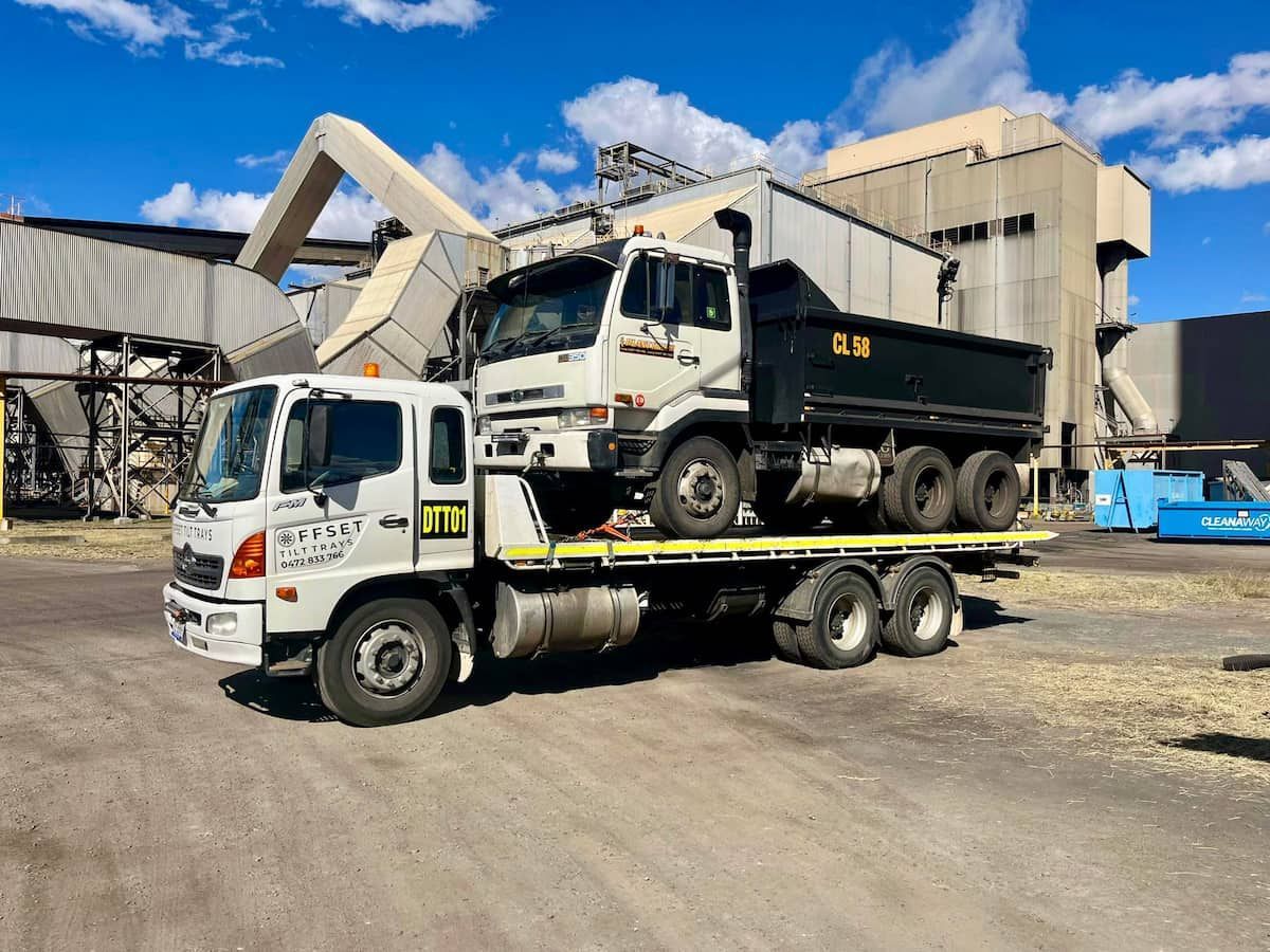 A Dump Truck Is Being Towed by A Tow Truck in A Parking Lot — Offset Tilt Trays In Biloela, QLD
