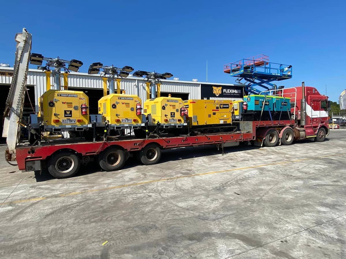 A Red Semi Truck Is Carrying A Row Of Yellow Machinery — Offset Tilt Trays In Biloela, QLD