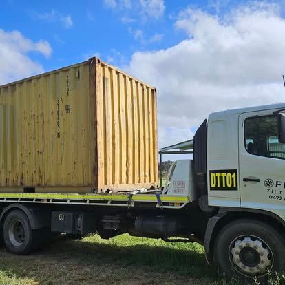 A Semi Truck With A Yellow Container On The Back Is Driving Down A Road — Offset Tilt Trays In Biloela, QLD