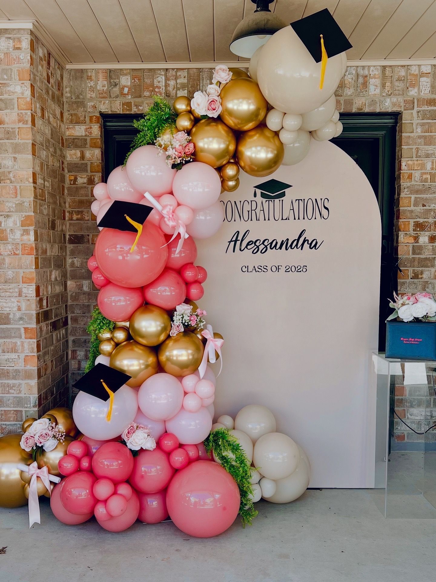 A bunch of balloons are sitting on a wooden deck in front of a house.