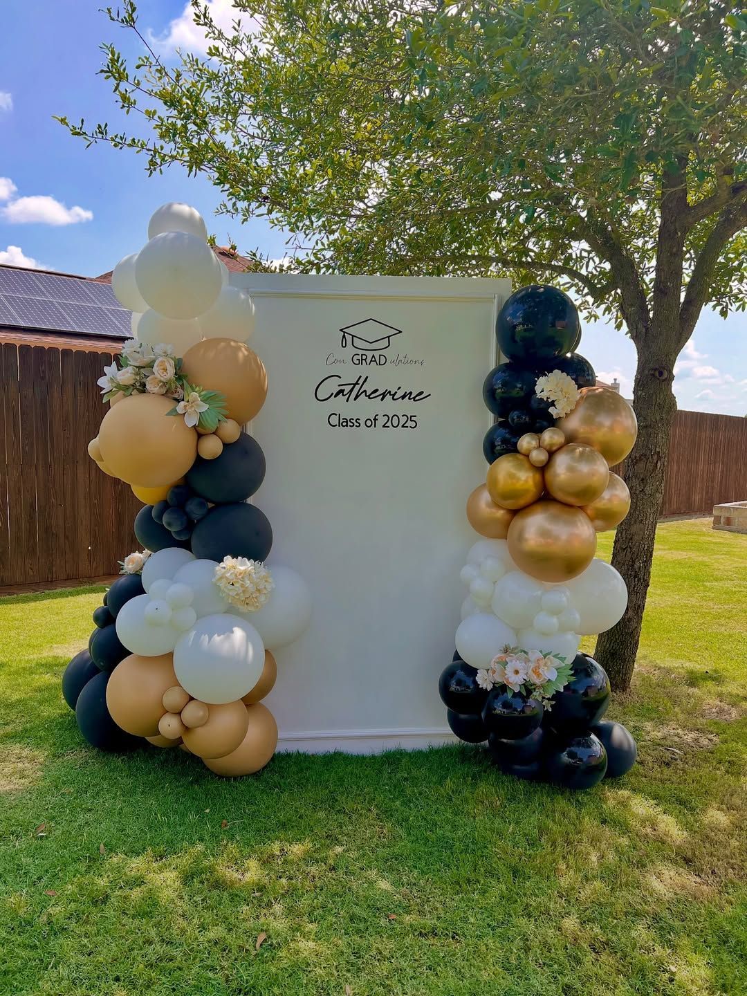 A bunch of balloons are sitting on top of a white wall in the grass.