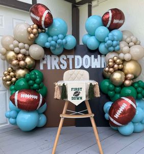A high chair decorated with balloons and a banner that says first down
