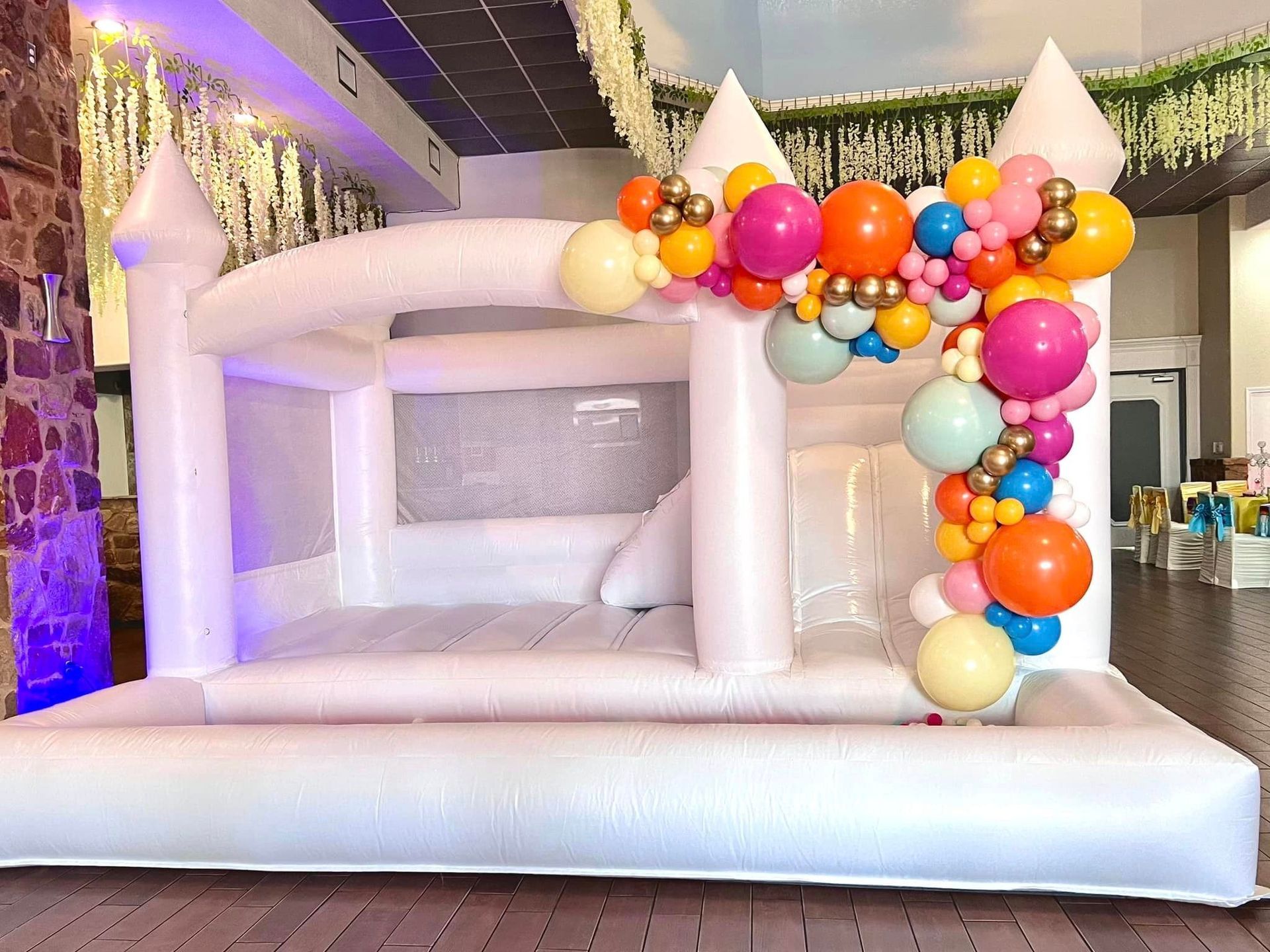 A white bouncy castle decorated with balloons in a room.