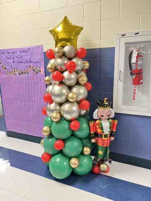 Balloon Christmas tree with nutcracker figure in hallway.