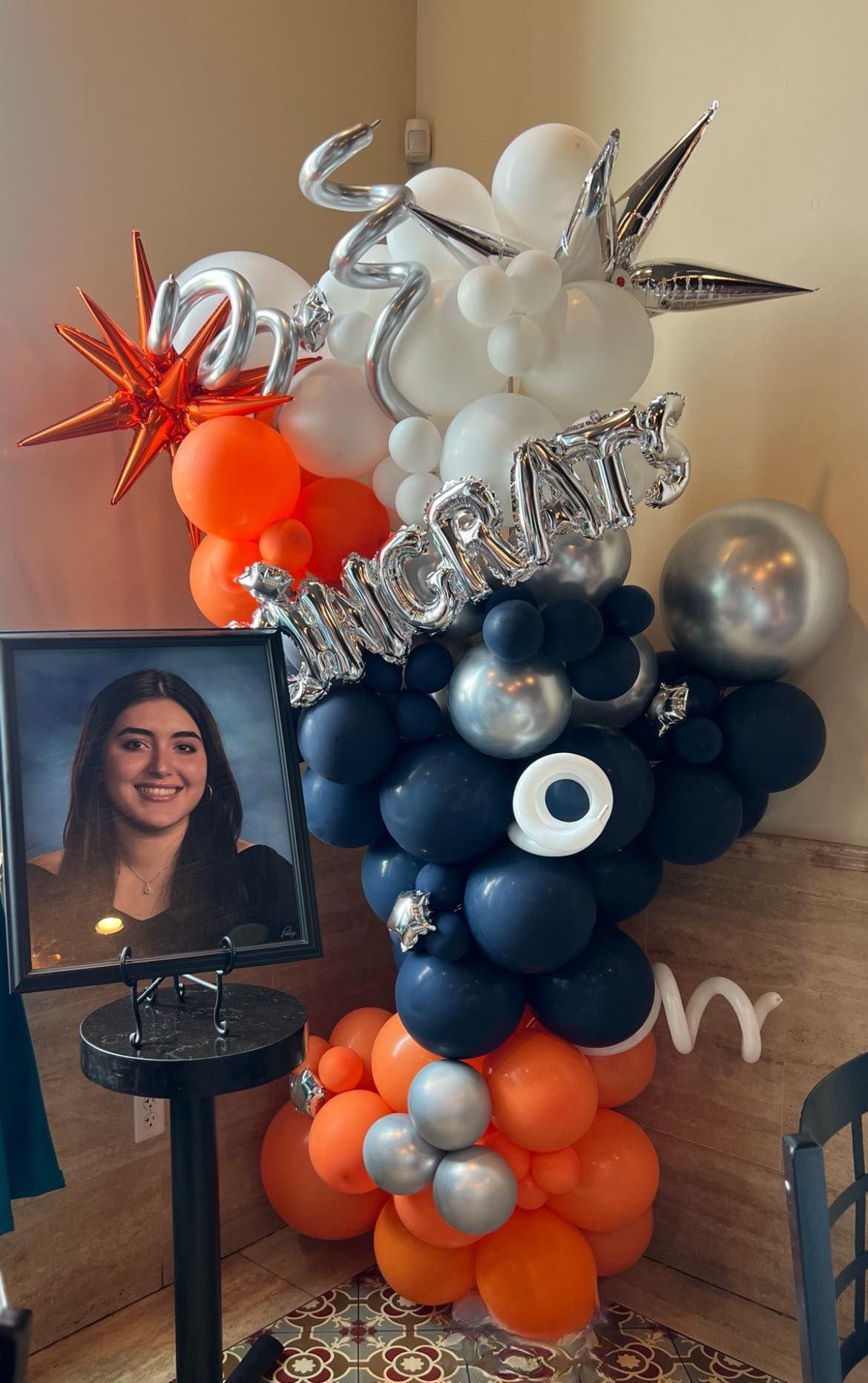 A bunch of balloons are sitting on a table next to a picture of a woman.