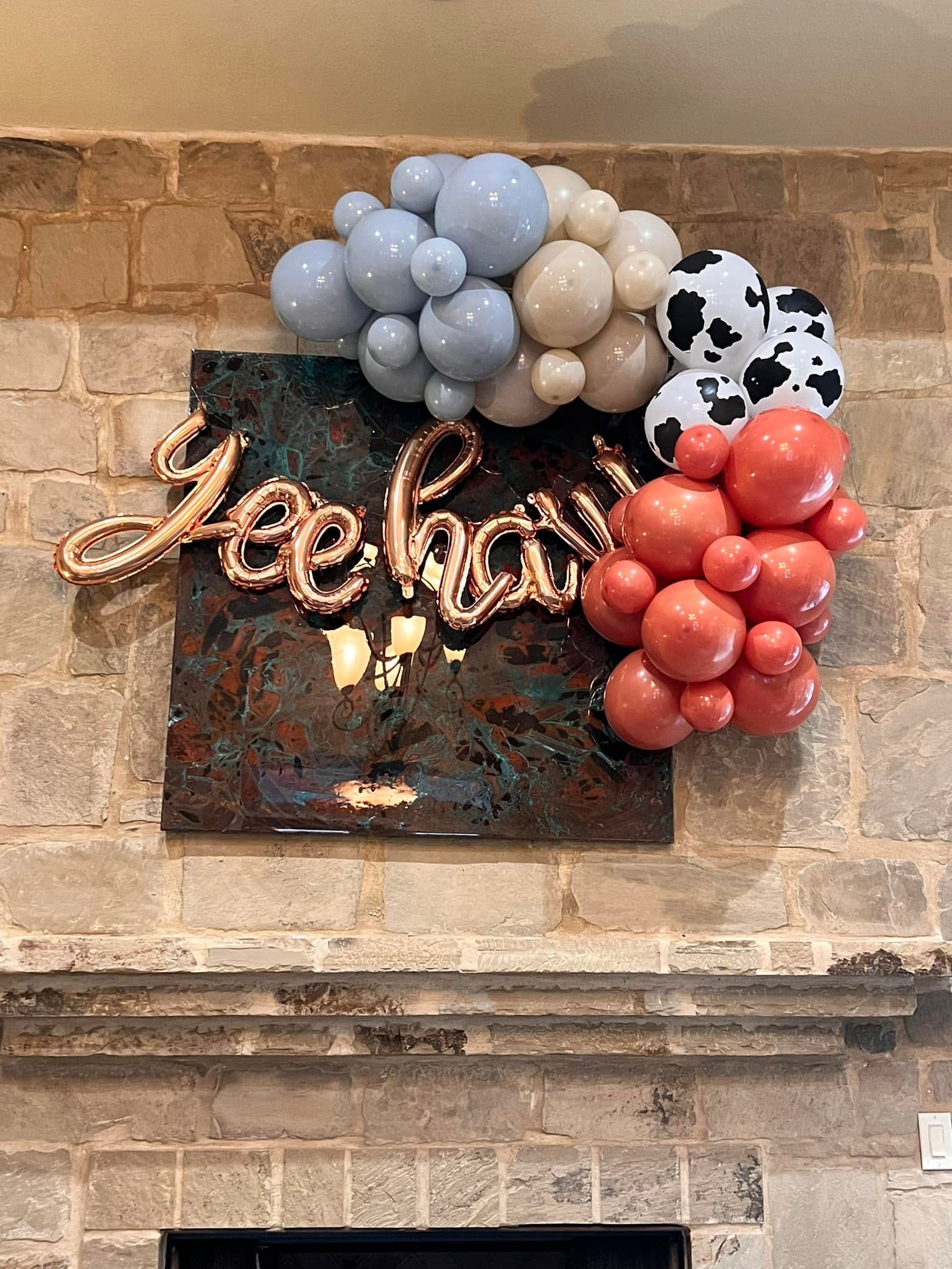 A bunch of balloons are hanging on a brick wall.