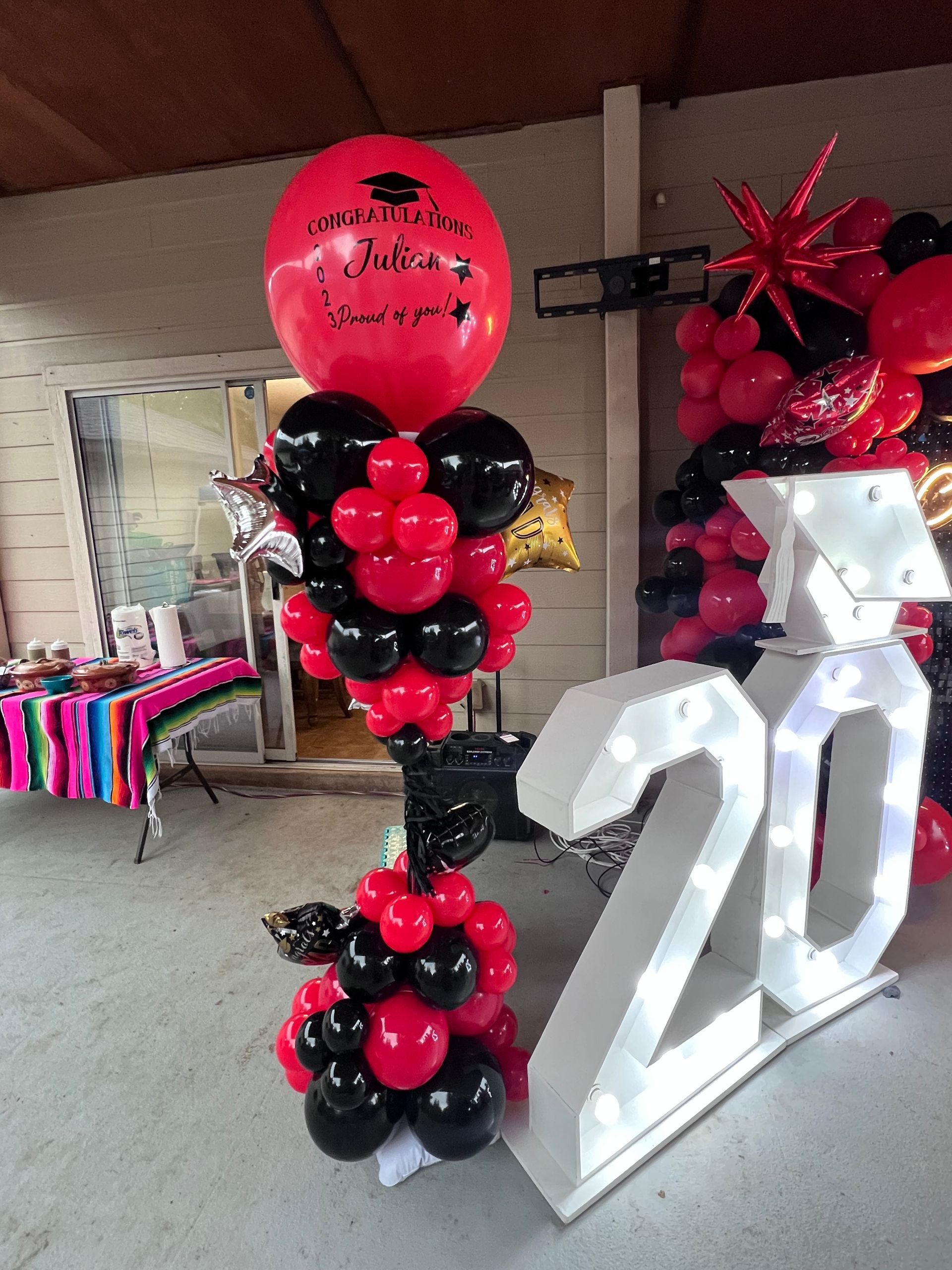 A bunch of red and black balloons on top of a white number 20