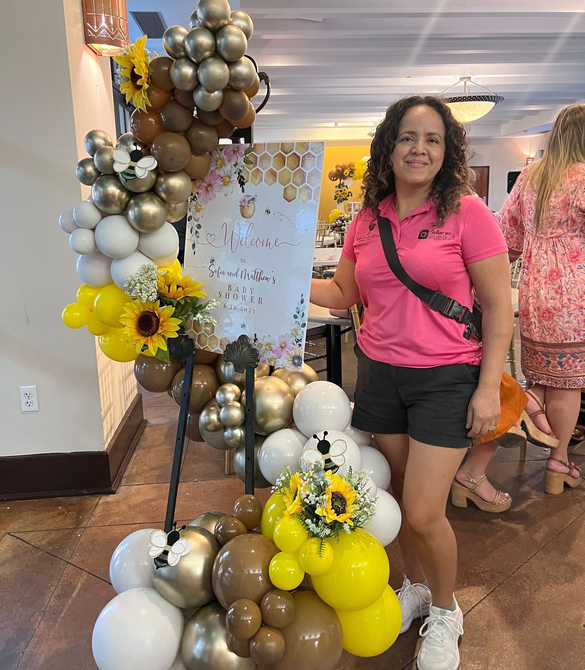 A woman is standing in front of a display of balloons and flowers.