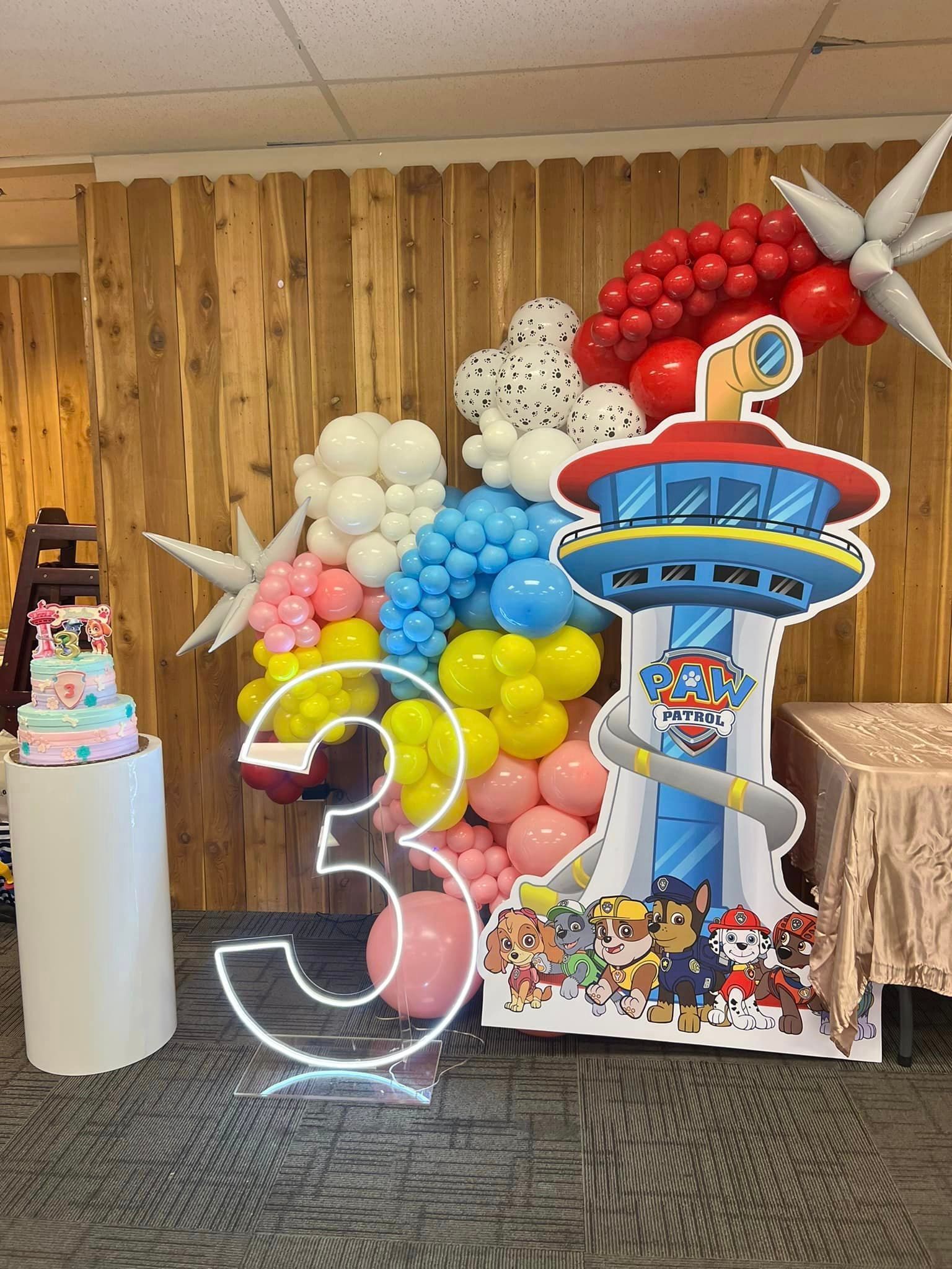 A room decorated with balloons and a paw patrol sign.