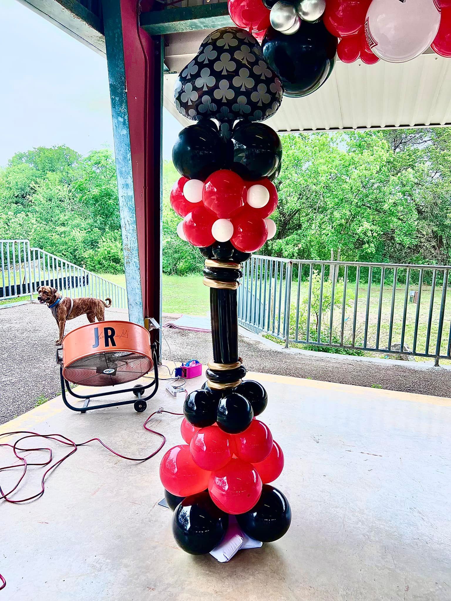 A balloon tower with red , black and white balloons in the shape of a mickey mouse head.