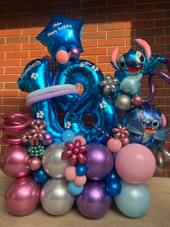 A bunch of balloons are sitting in front of a brick wall.