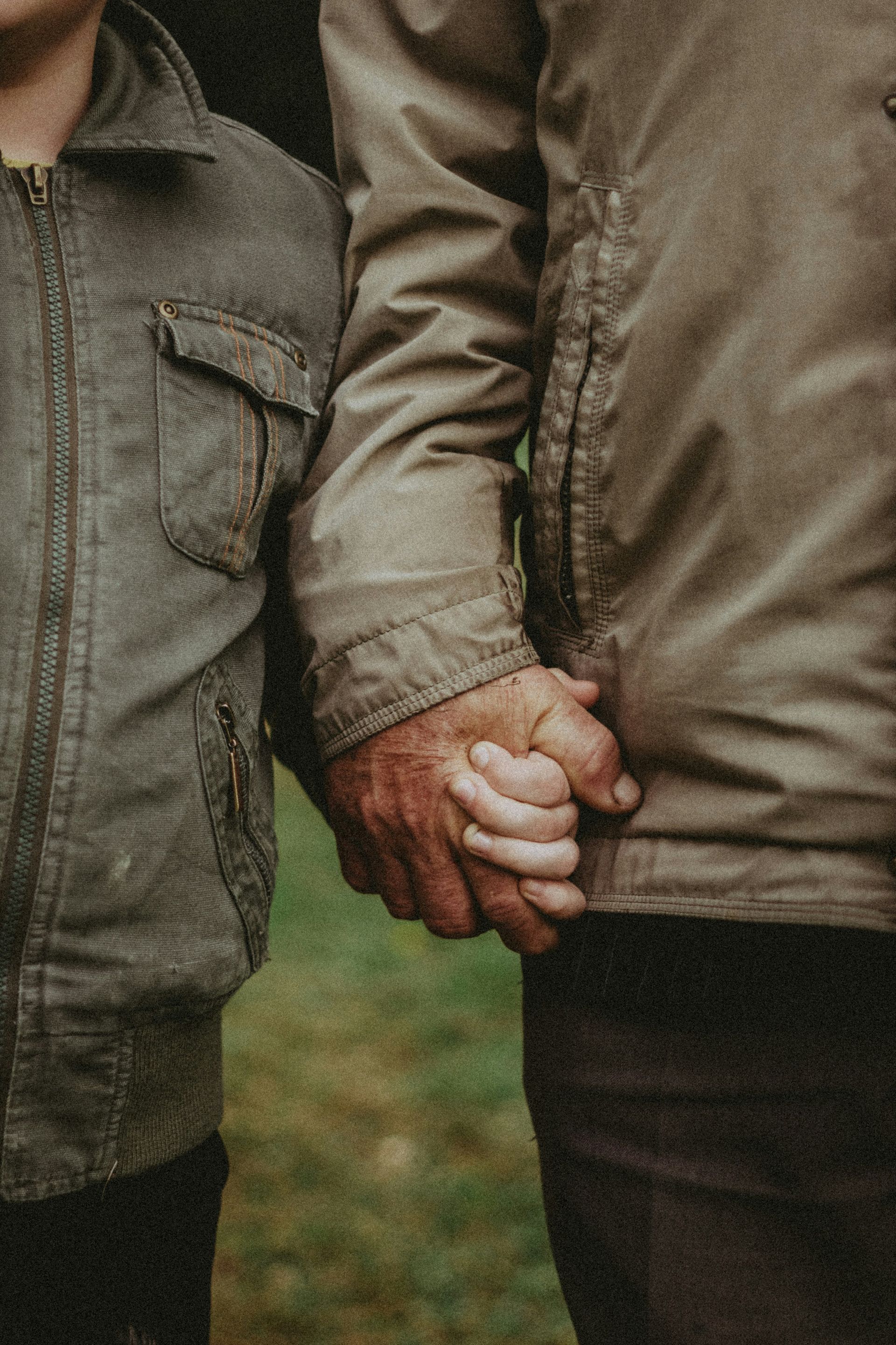 A man and a child are holding hands in a field.