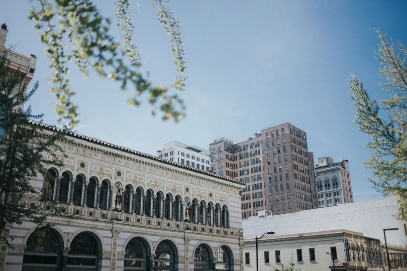 A large building with arches is surrounded by other buildings in a city.