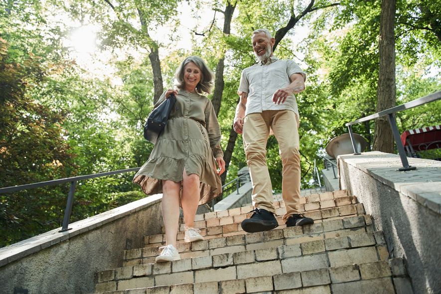 A man and a woman are walking down stairs in a park.