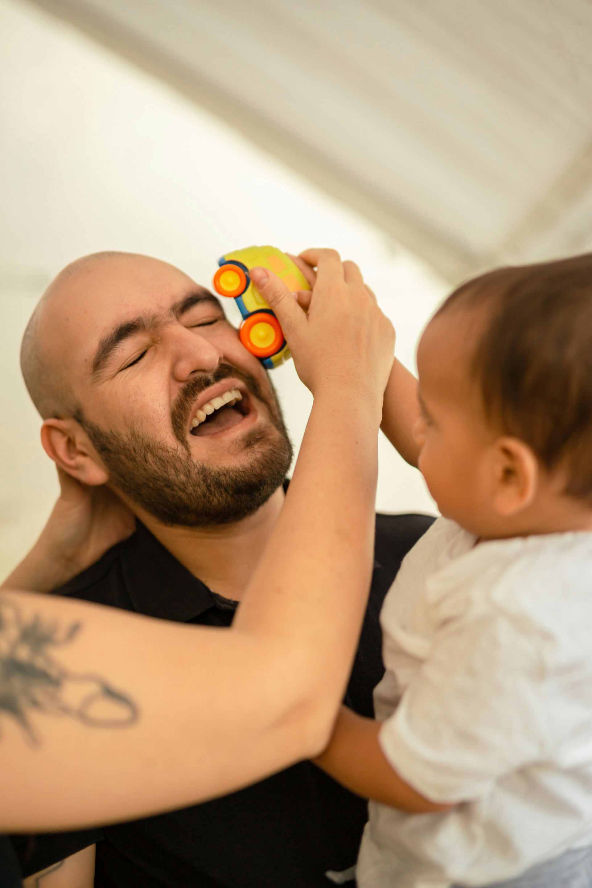 A man and a baby are playing with a toy car.